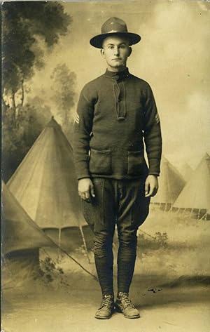 Postcard of World War I soldier, a studio shot in front a background scene ot conical pitched tents