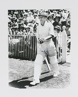 A signed photograph (black and white, 303 × 240 mm) of Don Bradman walking out to bat