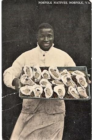 "NORFOLK NATIVES": TINTED, REAL-PHOTO POSTCARD OF AN AFRICAN-AMERICAN CHEF DISPLAYING A LARGE TRA...