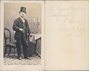 Homme en chapeau haut-de-forme un cigare à la main, chandelier posé sur une table, circa 1865