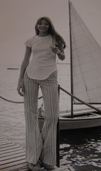 Blonde woman on dock with sailboat behind her.Photograph from the 1970 Cannes Film Festival.