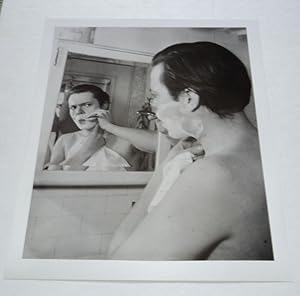 A BEAUTIFUL ORIGINAL PHOTOGRAPH OF A YOUNG ORSON WELLES SHAVING IN FRONT OF A MIRROR.