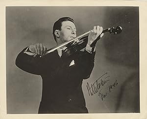 Half-length glossy publicity photograph of the noted violinist bowing his instrument