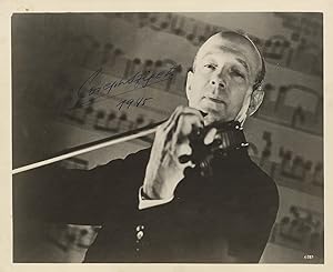 Half-length glossy publicity photograph of the noted violinist bowing his instrument