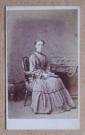 Carte De Visite Photograph: Portrait of a Woman Seated at a Desk & Holding a Book.