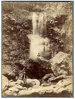 Hommes posant à côté d'une cascade. Un homme fait la sirène