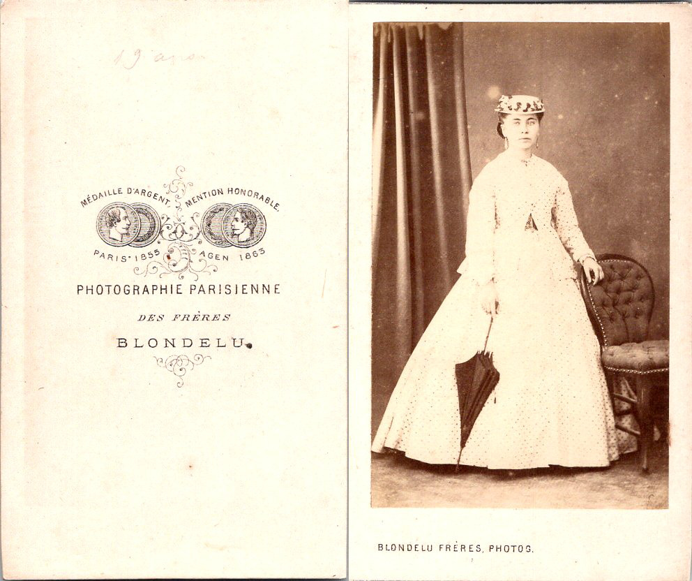 Blondelu Femme en robe claire en pose avec un canotier et une