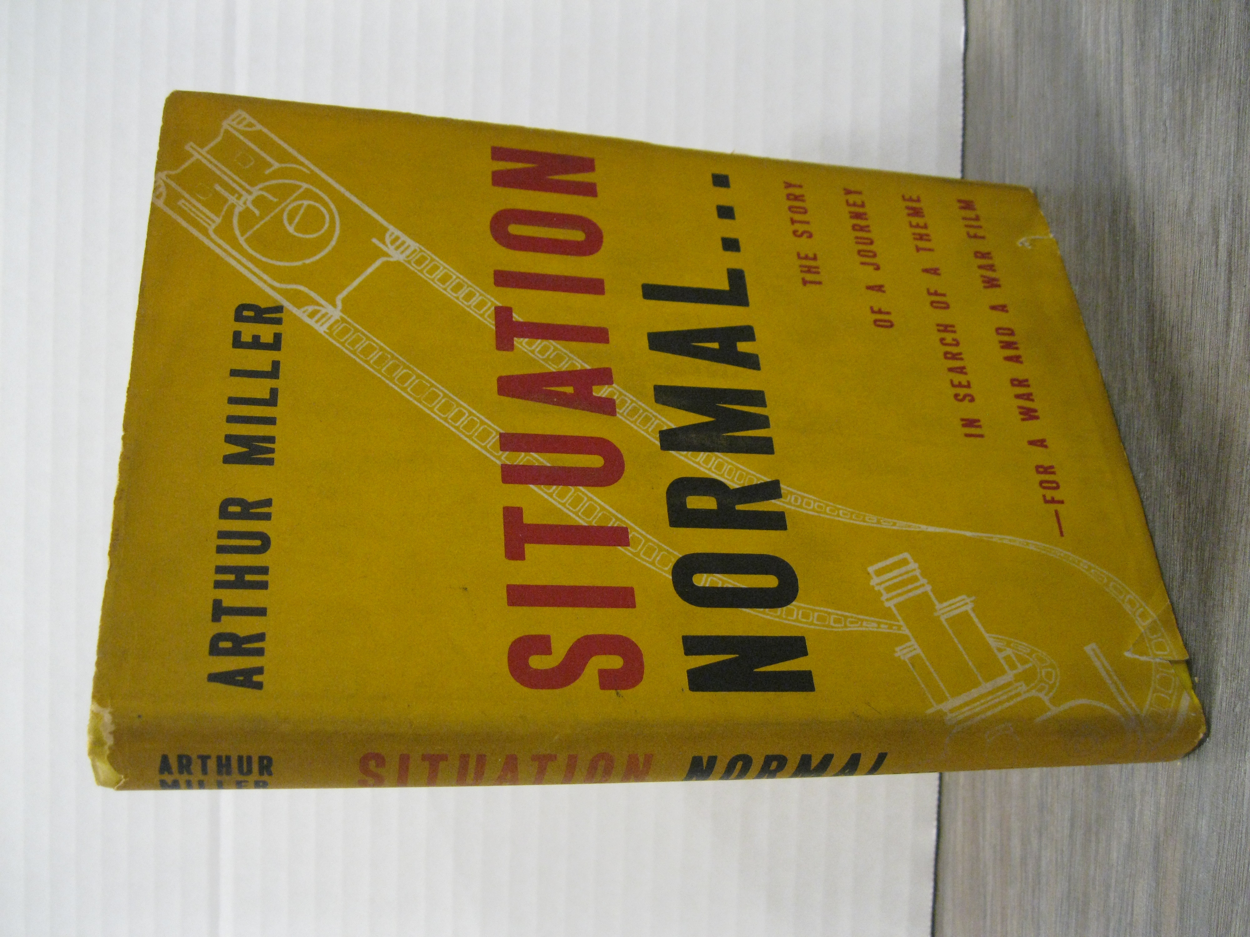 SITUATION NORMAL.THE STORY OF A JOURNEY IN SEARCH OF A THEME - FOR A WAR AND A WAR FILM *SIGNED* MILLER, ARTHUR [Very Good] [Hardcover] pp: 179. SIGNED FIRST EDITION. Yellow cloth covered boards, with red and black lettering on the spine and front board. A work of non-fiction by Miller that describes army life on military bases. He had written several plays before this book but this is his first published book (Ahearn, Collected Books, 1997). Printed on the cheaper war time paper. This copy has been inscribed on the free endpaper  To----Britton/Arthur Miller/Aug/53 . The yellow boards have some darkening in the centre (both front and back) that appears to have been a dye transfer. Although visible the darkening is not serious. The spine ends and corners are bumped and the top edge is soiled. The dust jacket has obvious darkening and soiling. There is about one-quarter inch chipped at the head of the spine, smaller chipping and a couple of short, closed tears on the extremities. Overall, a very good copy of this author's scarce first book, signed by Miller. The images should show these faults. Please inquiry is more photos are required.