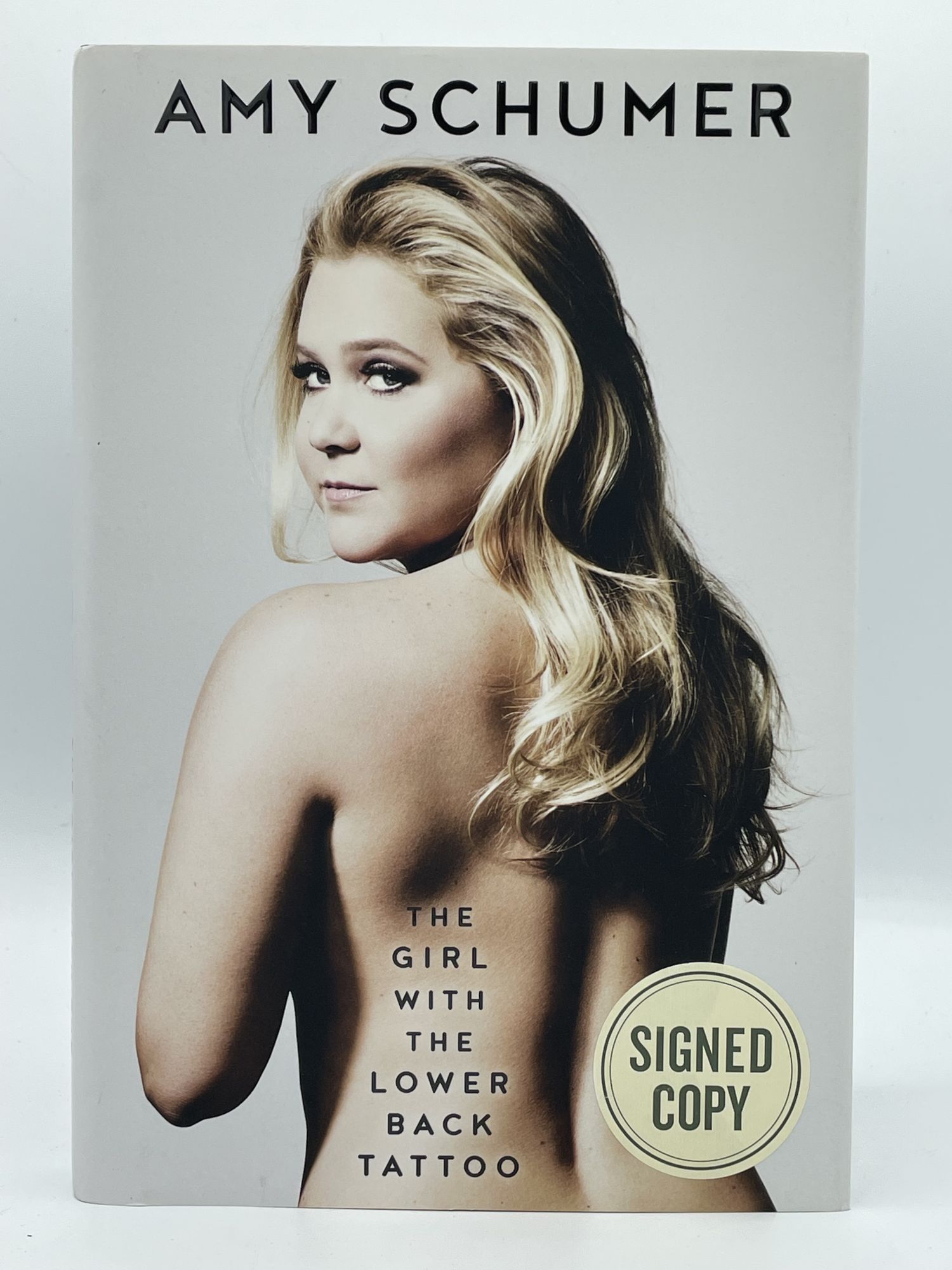 The Girl with the Lower Back Tattoo SCHUMER, Amy [SIGNED] [Very Good] [Hardcover] 8vo. Boards. Dust jacket. 323 pp. Minor jacket wear. Signed on publisher's tipped-in page. Autograph sticker on front jacket cover. This is a signed first edition memoir by the comedian Schumer.