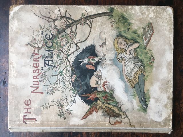 The Nursery 'Alice' Containing Twenty Coloured Enlargements from Tenniel's Illustrations to 'Alice's Adventures in Wonderland' with Text Adapted to Nursery Readers. The Cover Designed and Coloured by E. GERTRUDE THOMSON. Price One Shilling.