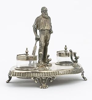 A silver-plated standish - a desk set holding pens and ink - featuring a 120 mm-high figure of W....