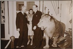 Malraux zusammen mit Frau und Museumsdirektor stehen hinter einem riesigen ausgestopften Löwen.