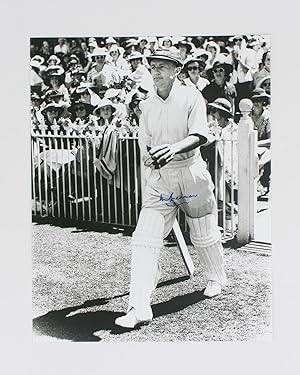 A signed photograph (black and white, 303 × 240 mm) of Don Bradman walking out to bat