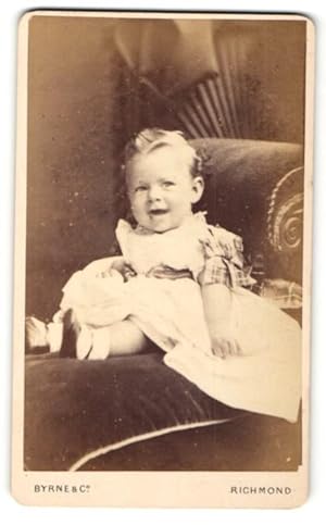Photo Byrne, Co., Richmond, Portrait sitzendes Kleinkind im weissen Kleid mit Schleifchen