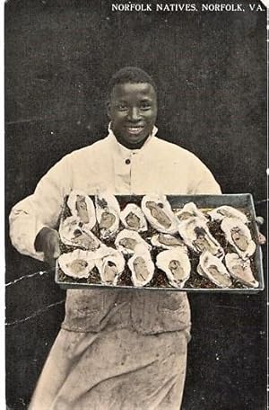 "NORFOLK NATIVES": TINTED, REAL-PHOTO POSTCARD OF AN AFRICAN-AMERICAN CHEF DISPLAYING A LARGE TRA...