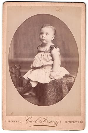 Bild des Verkufers fr Fotografie Carl Freund, Elberfeld, Portrait niedliches Kleinkind im hbschen Kleid auf Tisch sitzend zum Verkauf von Bartko-Reher