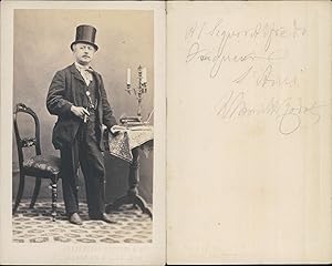 Homme en chapeau haut-de-forme un cigare à la main, chandelier posé sur une table, circa 1865