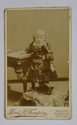 Carte De Visite Photograph: A Charming Studio Portrait of a Young Girl Beside a Table.