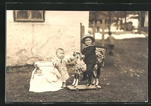 Ansichtskarte zwei niedliche Kleinkinder spielen mit einem Schaukelpferd im Garten