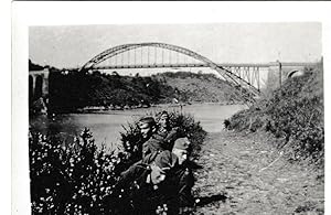 Soldatengruppe am Flussufer mit Bogenbrücke - Photographie