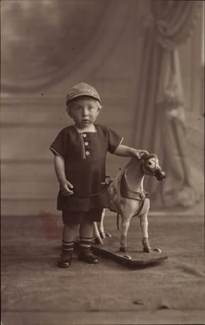 Foto Ansichtskarte / Postkarte Kleiner Junge neben einem Schaukelpferd auf Rollen