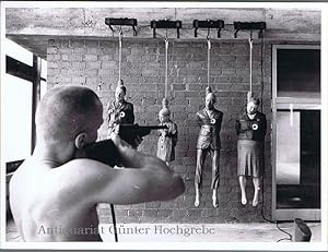 Mann schießt auf vier aufgehängte Menschenpuppen. Installation - Performance. Unbekannter Künstler.