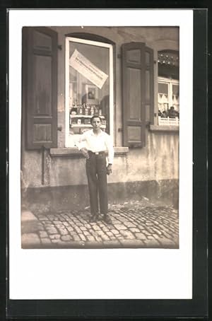 Foto-Ansichtskarte Junger Mann steht vor dem Schaufenster eines Geschäftes