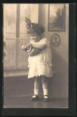 Foto-Ansichtskarte Kleines Mädchen mit Puppe auf dem Arm