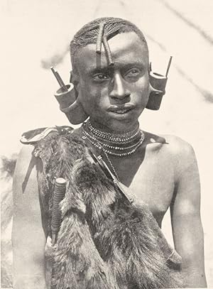 Imagen del vendedor de An Andorobo man - The Andorobo, who are closely related to the Nandi tribe, and whose language is practically only a dialect of Nandi, are a mixture of many negro races. They dress their hair like the pastoral Masai, to whom they have more or less attached themselves, and wear in the lobe of the ear an extraordinary wooden cylinder a la venta por Antiqua Print Gallery