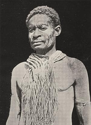 Imagen del vendedor de A Kiwai man in mourning costume - A man in mourning is never secluded, and wears a sogere of grass round his neck; at the back it hangs down to his ankles. As time passes the man will substitute a sogere of smaller size for the large one, but a small grass necklace of that kind is worn both by men and women for many months after a death a la venta por Antiqua Print Gallery