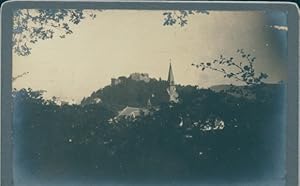 Foto Unbekannter Ort, Blick über einen Ort zur einer Burgruine, Kirchturm
