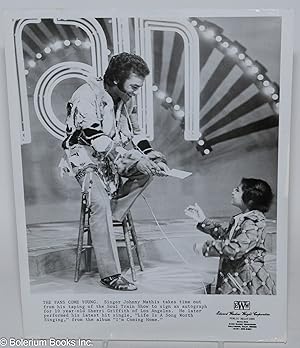 Glossy b&w 8x10 publicity photograph of Johnny Mathis signing a fan's program