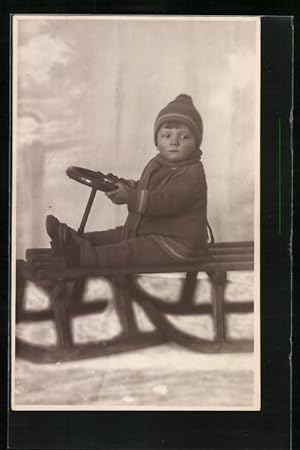 Foto-Ansichtskarte Kleiner Junge auf einem Schlitten im Winter