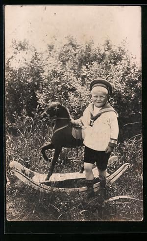 Foto-Ansichtskarte Kleiner Junge in Matrosenkleidung mit einem Schaukelpferd