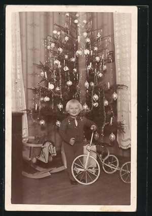 Foto-Ansichtskarte Bube mit Schaukelpferd und Dreirad am Weihnachtsbaum stehend