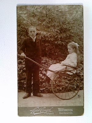 Kabinettfoto, Junge zieht Mädchen in einem Rollstuhl, Wiesbaden, Fotografie, ca. 1900
