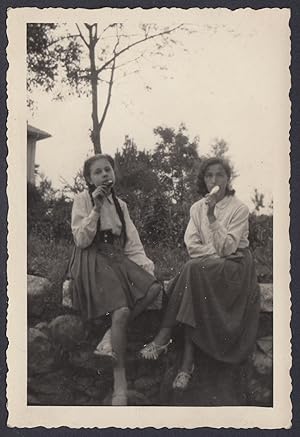 Due giovani donne mangiano gelato su muretto, 1950 Fotografia vintage
