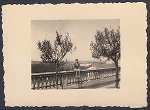Ragazzo seduto su balaustra con sfondo paese da identificare, 1940 Fotografia vintage