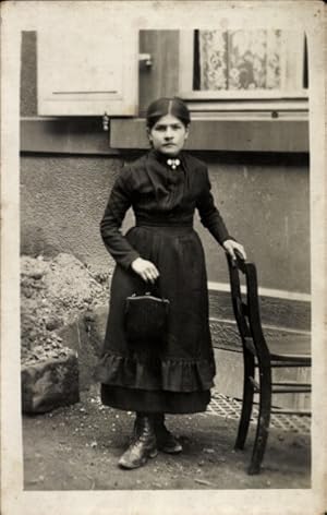 Foto Ansichtskarte / Postkarte Junge Frau in schwarzem Kleid, Portrait, Handtasche, Stuhl