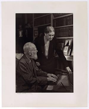 Portrait of George Bernard Shaw playing the spinet with Blanche Patch, his secretary, looking on.