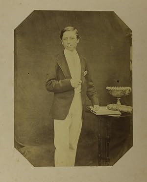 Albumen portrait photograph, three -quarter length standing at a table, aged about 16; corner tri...